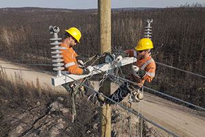 Two Hydro workers on a new hydro pole making repairs to equipment.