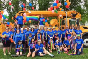 Manitoba Hydro volunteers in front of a bucket truck decorated for the Pride parade.