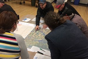 People gathered around a table with a map laid out.